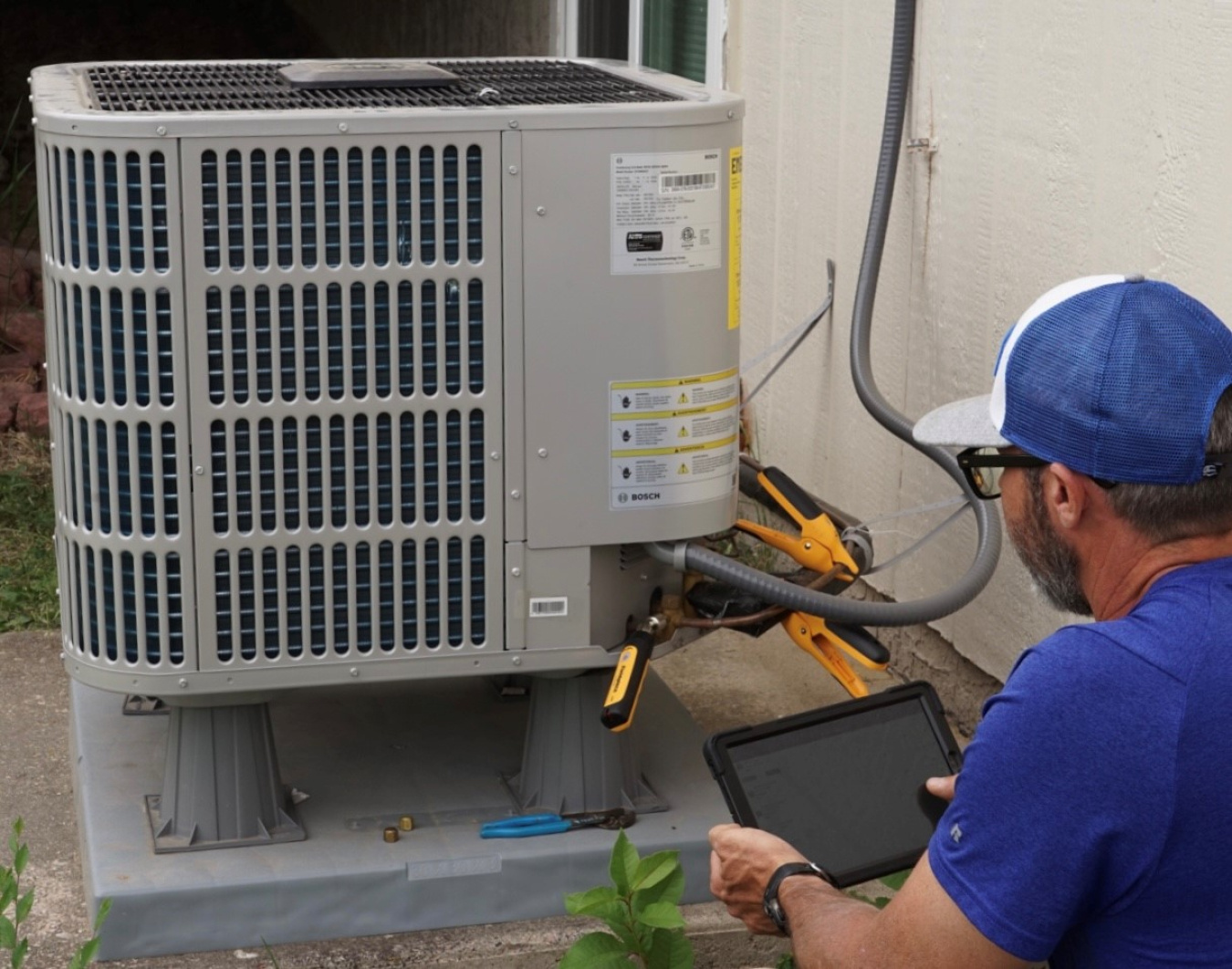 Technician checking a residential heat pump unit, a common home energy rebate category.