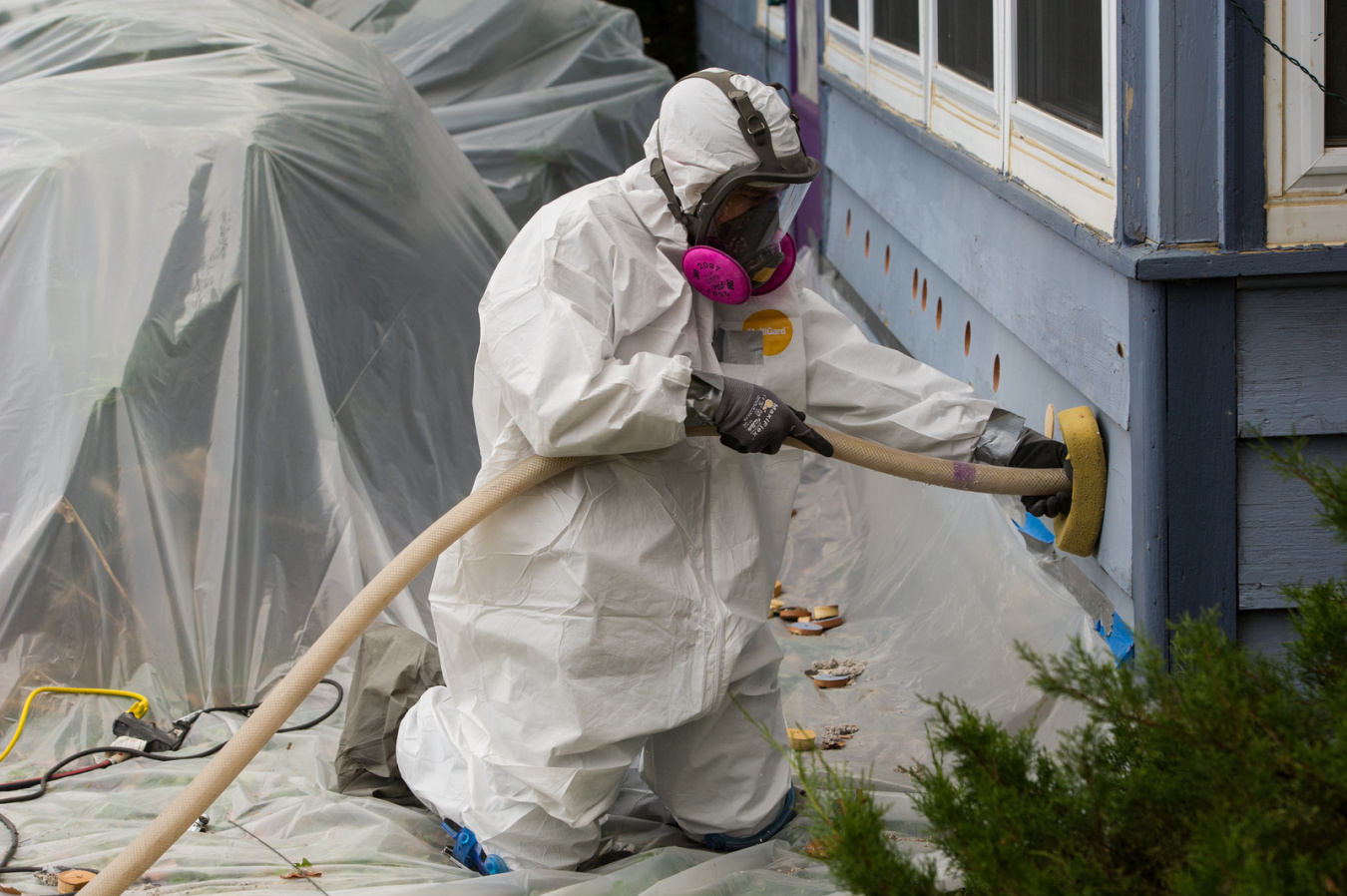 Weatherization worker installing insulation into a house wall for a low-income home energy assistance guide.